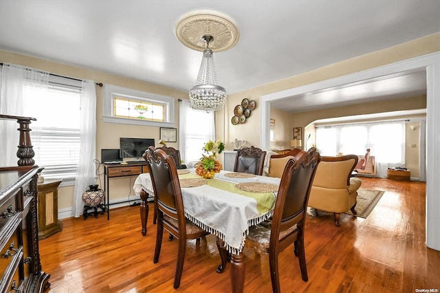 dining space featuring an inviting chandelier, a healthy amount of sunlight, and wood-type flooring