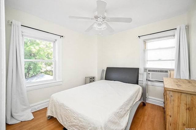 bedroom with ceiling fan, cooling unit, and wood-type flooring