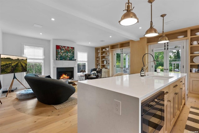 kitchen with wine cooler, light brown cabinetry, an island with sink, and a healthy amount of sunlight