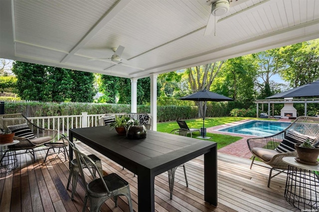 wooden terrace featuring a fenced in pool, ceiling fan, and a lawn