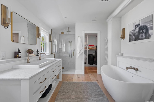 bathroom with wood-type flooring, vanity, and independent shower and bath