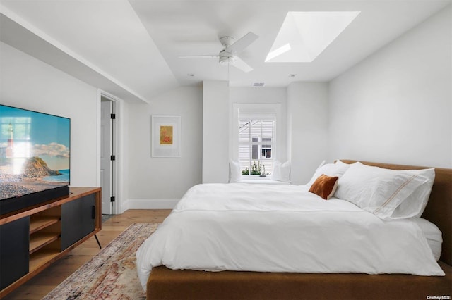 bedroom featuring hardwood / wood-style floors, ceiling fan, and vaulted ceiling with skylight