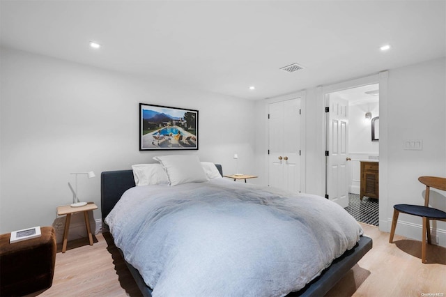 bedroom with ensuite bath and light hardwood / wood-style flooring