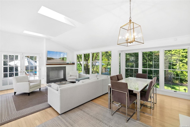 interior space featuring a notable chandelier, french doors, lofted ceiling, and light wood-type flooring