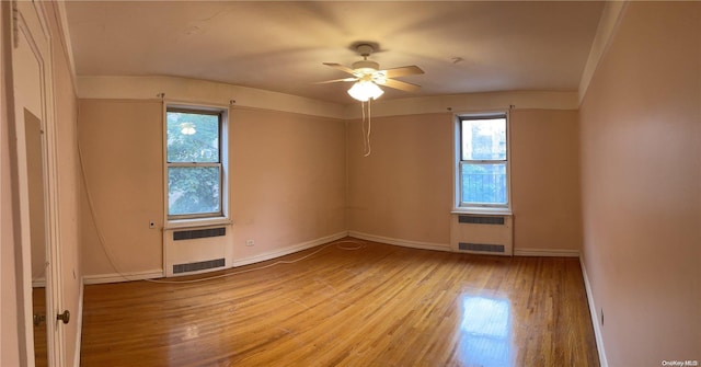 unfurnished room with radiator heating unit, light hardwood / wood-style flooring, and a wealth of natural light