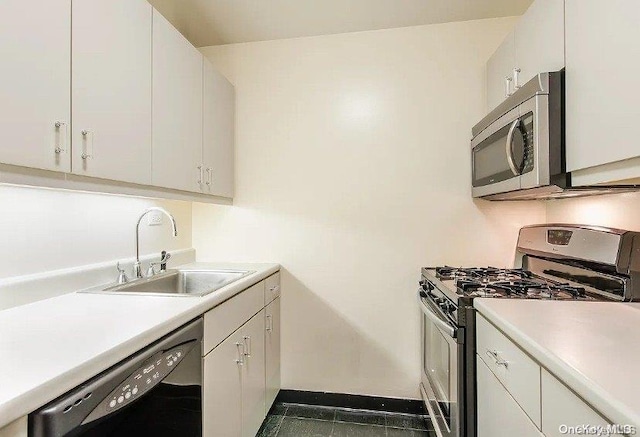 kitchen with white cabinetry, sink, stainless steel appliances, and dark tile patterned flooring