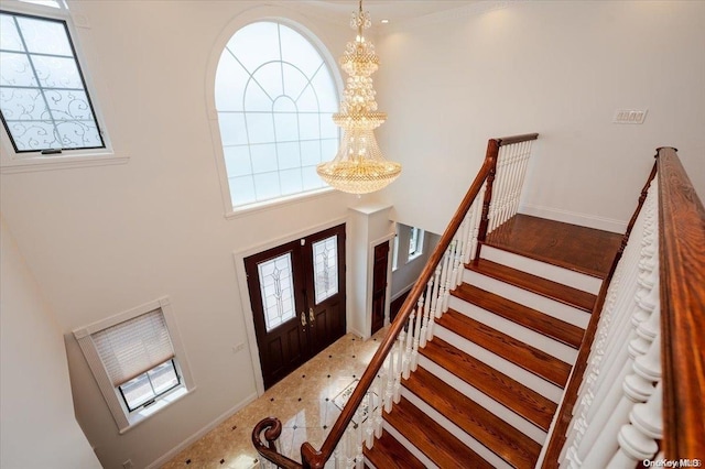 carpeted foyer entrance featuring a towering ceiling, plenty of natural light, and a notable chandelier