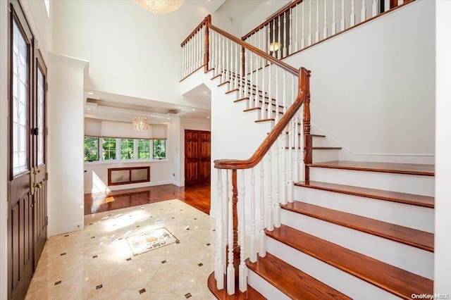 entryway with a notable chandelier, wood-type flooring, and a high ceiling