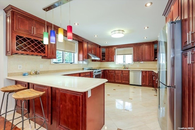 kitchen featuring kitchen peninsula, tasteful backsplash, stainless steel appliances, pendant lighting, and a breakfast bar area