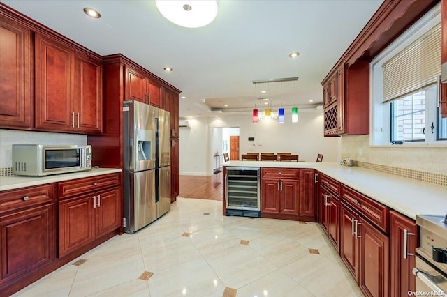 kitchen with kitchen peninsula, appliances with stainless steel finishes, light tile patterned floors, wine cooler, and hanging light fixtures