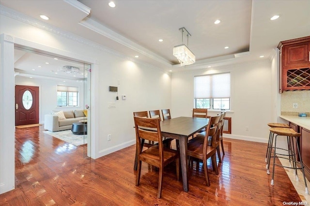 dining room featuring a raised ceiling, a wealth of natural light, and light hardwood / wood-style flooring