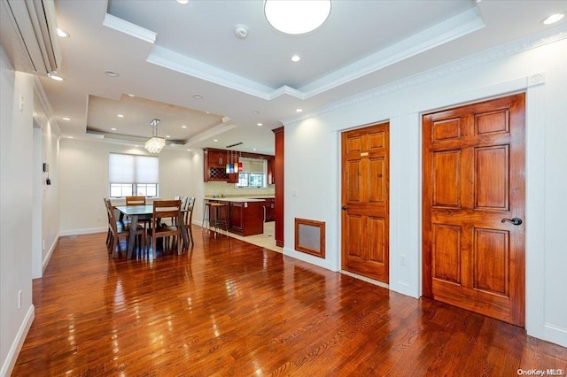 dining room featuring dark hardwood / wood-style flooring, a raised ceiling, and crown molding