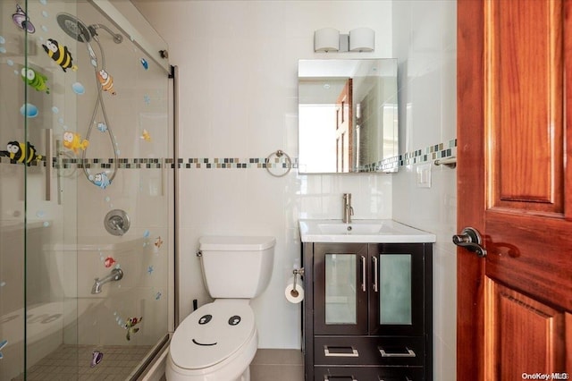 bathroom with vanity, toilet, a shower with shower door, and tile walls