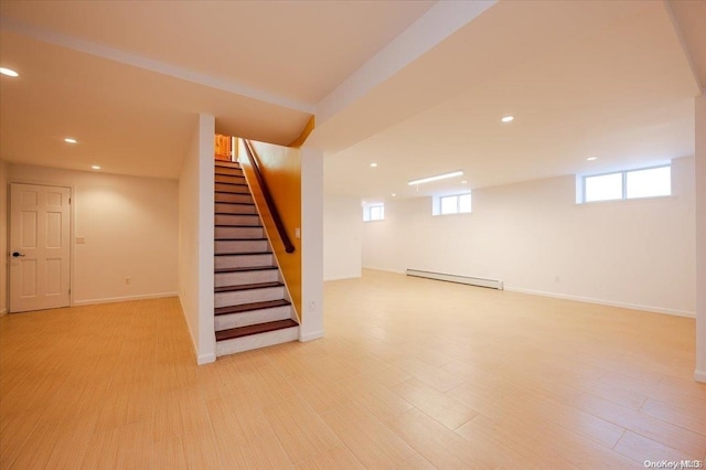 basement featuring light wood-type flooring and baseboard heating