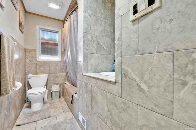 bathroom featuring shower / bath combo with shower curtain, toilet, tile walls, and crown molding