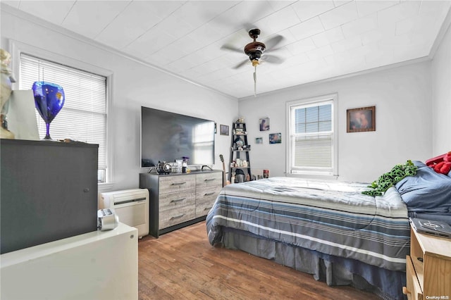 bedroom featuring ceiling fan, dark hardwood / wood-style flooring, crown molding, and a wall mounted AC