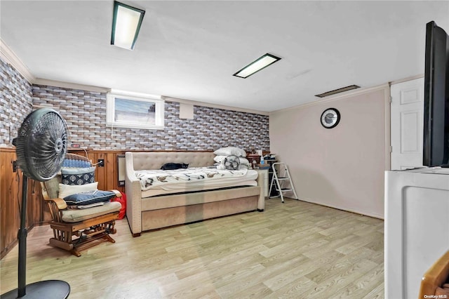 bedroom featuring light hardwood / wood-style floors, ornamental molding, and brick wall