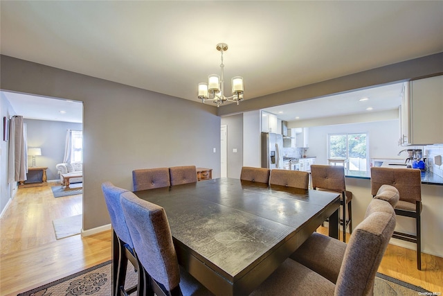 dining space featuring light hardwood / wood-style floors and an inviting chandelier