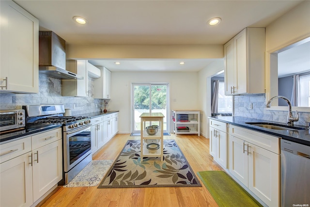 kitchen featuring white cabinetry, sink, wall chimney exhaust hood, and stainless steel appliances