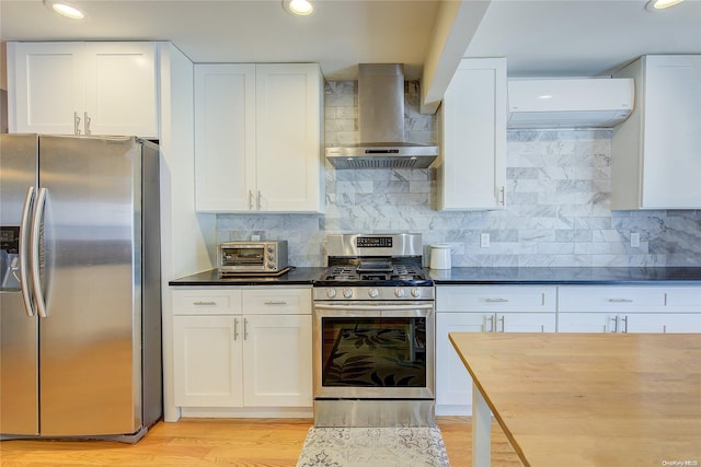 kitchen with white cabinetry, light wood-type flooring, wall chimney range hood, and appliances with stainless steel finishes