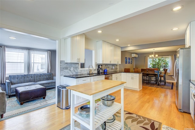 kitchen featuring white cabinetry, stainless steel appliances, backsplash, pendant lighting, and light wood-type flooring