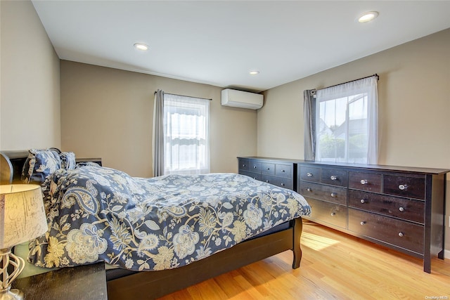 bedroom with a wall mounted air conditioner and light hardwood / wood-style floors