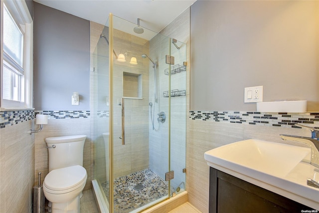 bathroom featuring vanity, toilet, tile walls, and walk in shower