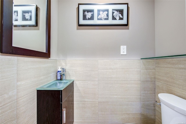 bathroom featuring vanity, toilet, and tile walls