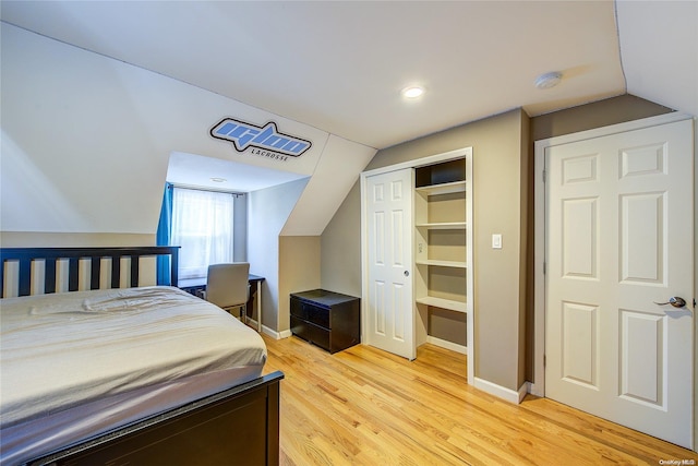 bedroom featuring a closet, wood-type flooring, and lofted ceiling