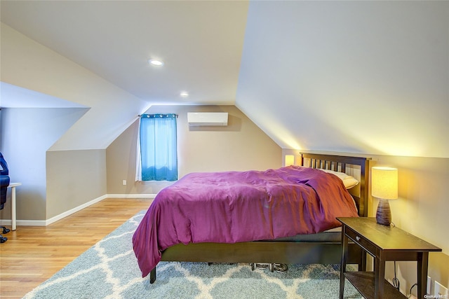 bedroom with an AC wall unit, wood-type flooring, and vaulted ceiling