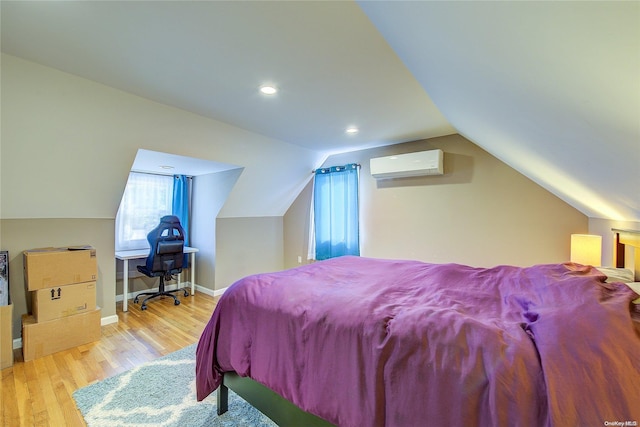 bedroom with a wall mounted air conditioner, vaulted ceiling, and light hardwood / wood-style flooring