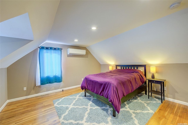 bedroom featuring a wall mounted AC, hardwood / wood-style floors, and vaulted ceiling