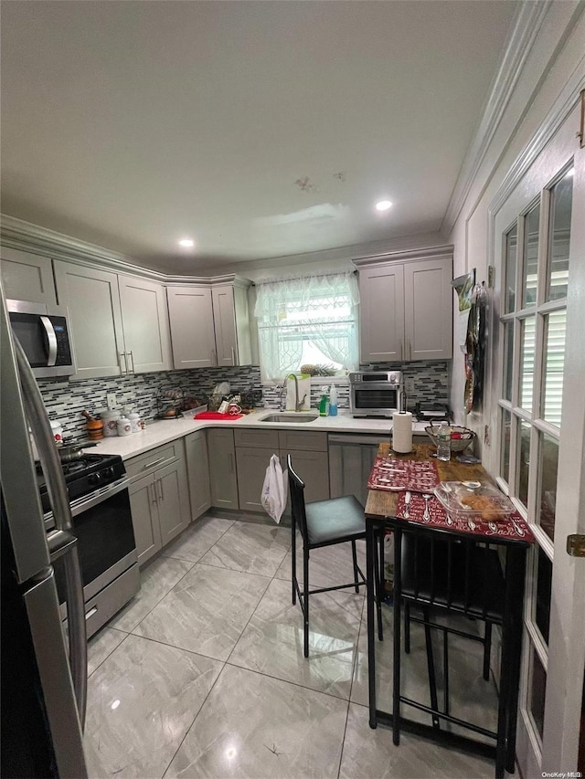 kitchen featuring crown molding, sink, gray cabinets, tasteful backsplash, and stainless steel appliances