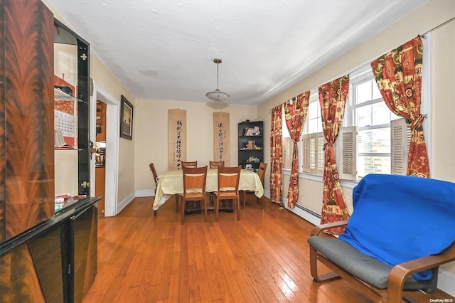 dining area with wood-type flooring and a baseboard radiator