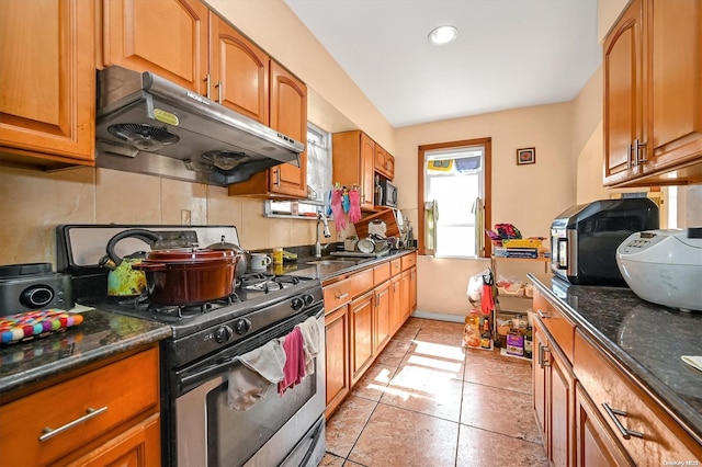 kitchen featuring dark stone countertops, sink, light tile patterned floors, and appliances with stainless steel finishes