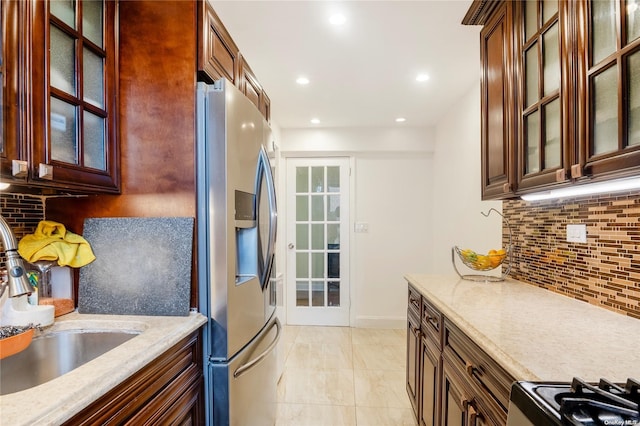 kitchen featuring stainless steel appliances, light stone counters, tasteful backsplash, and sink