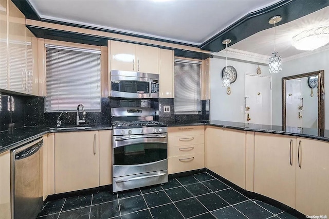 kitchen featuring sink, dark tile patterned floors, ornamental molding, appliances with stainless steel finishes, and decorative light fixtures