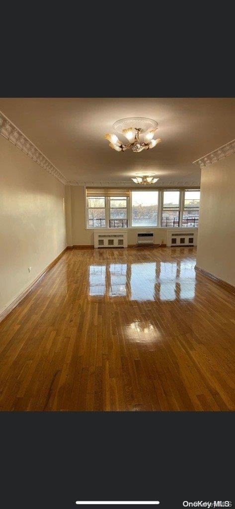 spare room featuring hardwood / wood-style floors and a chandelier