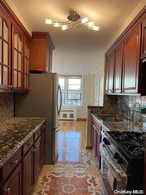 kitchen featuring appliances with stainless steel finishes, tasteful backsplash, dark stone countertops, and sink