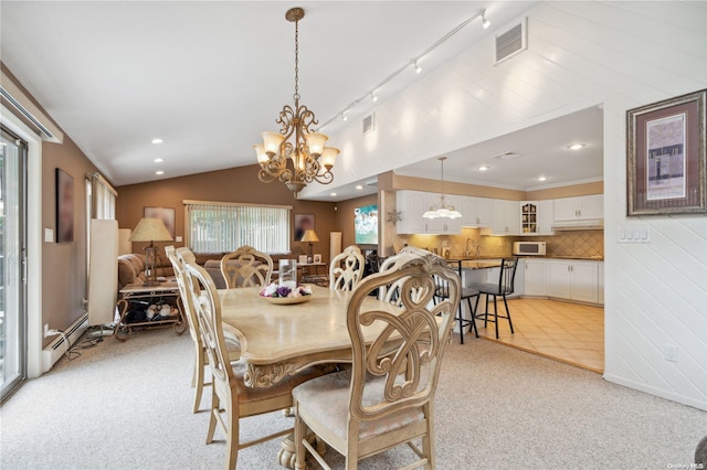 dining room with track lighting, light colored carpet, vaulted ceiling, a baseboard heating unit, and a chandelier