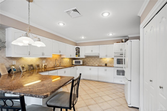 kitchen with a kitchen breakfast bar, white appliances, crown molding, sink, and decorative light fixtures