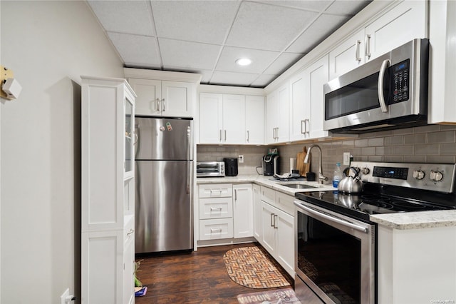 kitchen with sink, dark hardwood / wood-style floors, decorative backsplash, appliances with stainless steel finishes, and white cabinetry