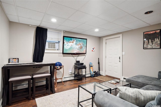 living room with dark hardwood / wood-style flooring, cooling unit, a drop ceiling, and a baseboard heating unit