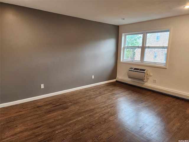 spare room featuring dark hardwood / wood-style flooring, an AC wall unit, and baseboard heating