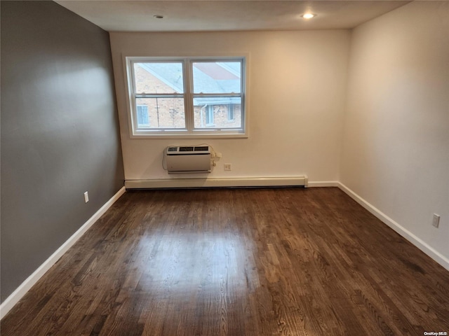 spare room with baseboard heating, dark wood-type flooring, and a wall unit AC