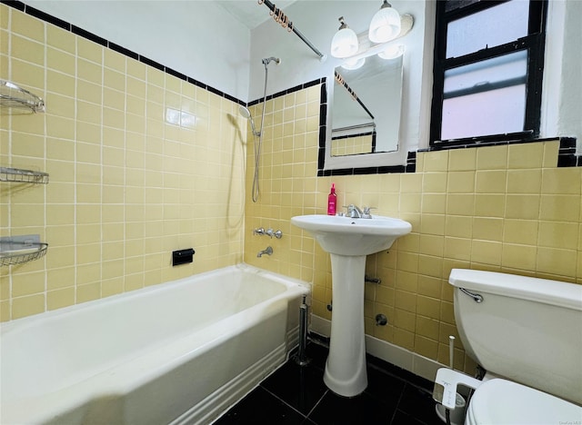full bathroom with shower / bath combination, tile walls, toilet, tile patterned floors, and a sink