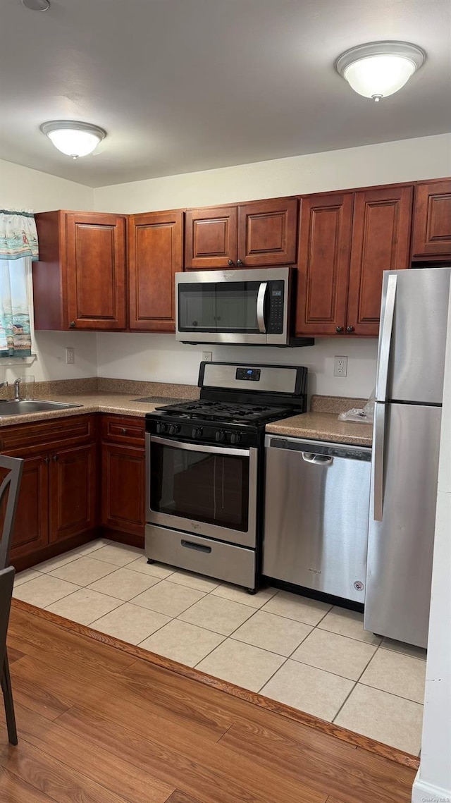 kitchen with sink, light tile patterned flooring, and appliances with stainless steel finishes