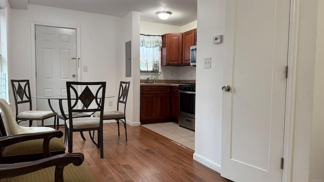 kitchen featuring range, sink, electric panel, and light hardwood / wood-style flooring