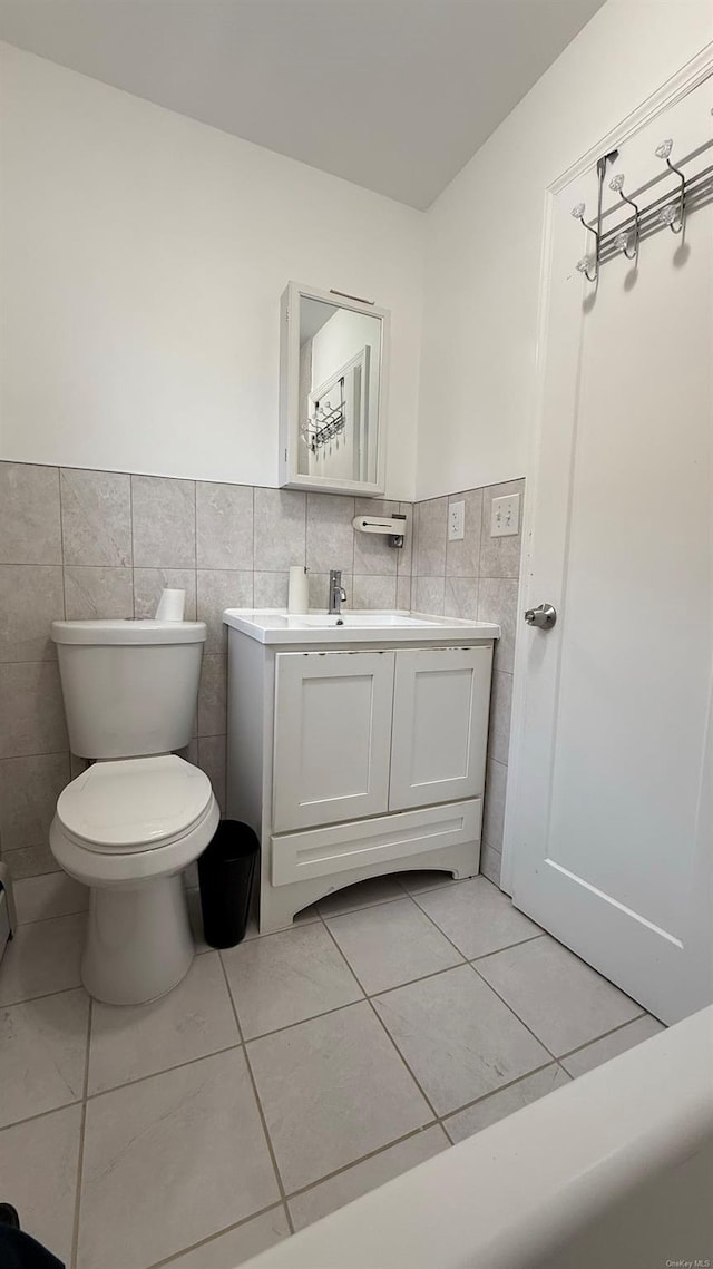 bathroom featuring tile patterned floors, vanity, tile walls, and toilet