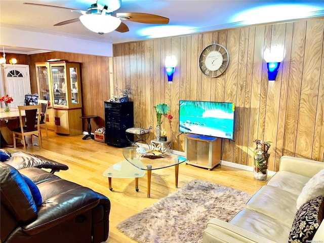 living room with wood walls, wood-type flooring, and ceiling fan with notable chandelier